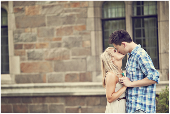 A young couple shares a kiss near stone architecture