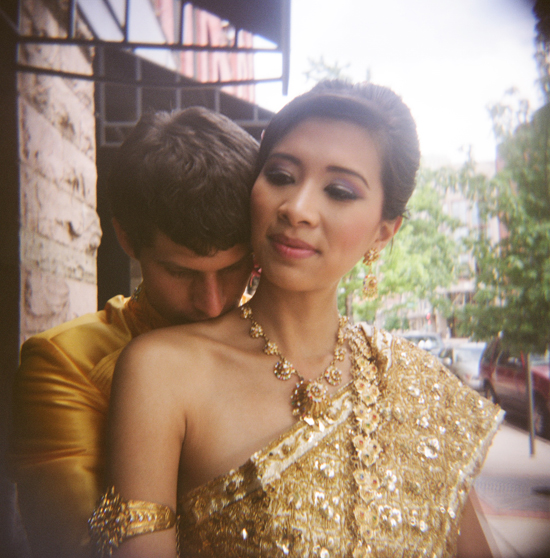 Bride in gold Thai dress embraced by groom