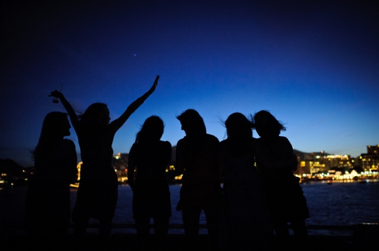 Silhouetted friends celebrate under the night sky by the sea
