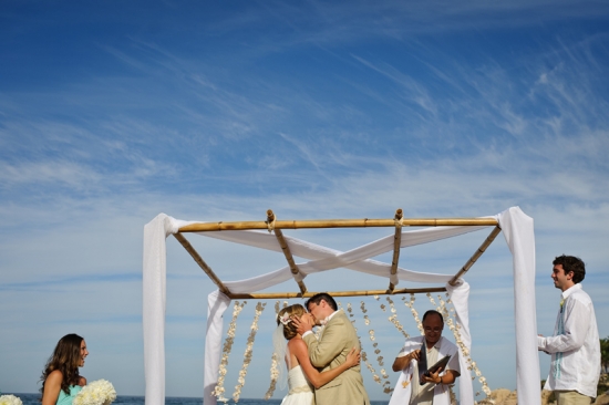 Bride and groom share first kiss at beach wedding