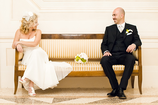 Bride and groom pose elegantly on a bench