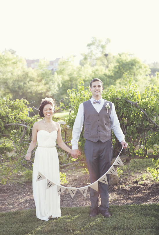 Happy newlywed couple with a Thank You banner