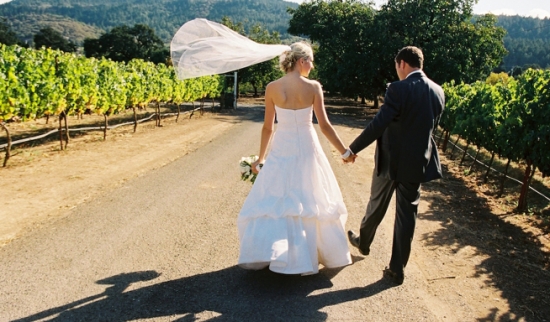 Bride and groom walking away after wedding ceremony in vineyard