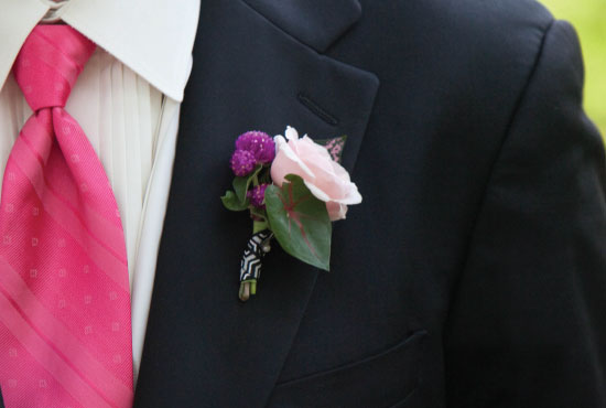 Groom's pink tie and boutonniere on a black suit jacket