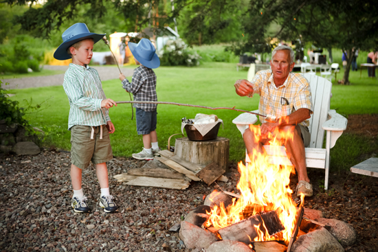 Grandfather and grandsons roasting marshmallows by campfire