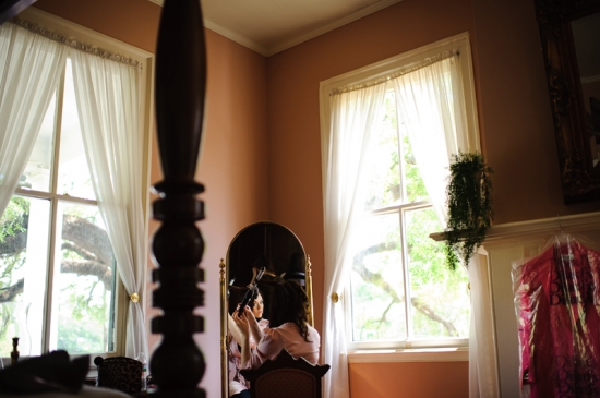 Bride getting ready by mirror in bright room