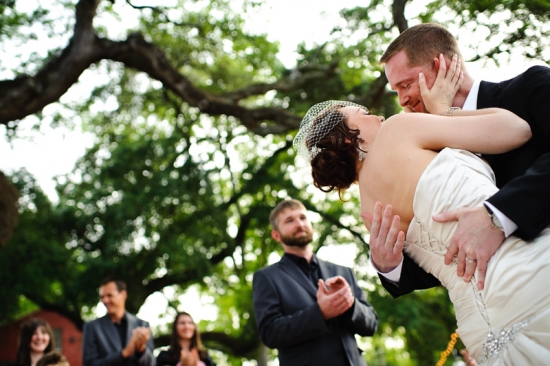 Bride and groom embrace under a tree at their wedding