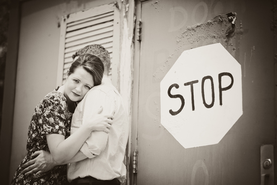 Black and white photo of couple embracing near a stop sign