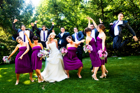 Wedding party in purple dresses jumping for joy