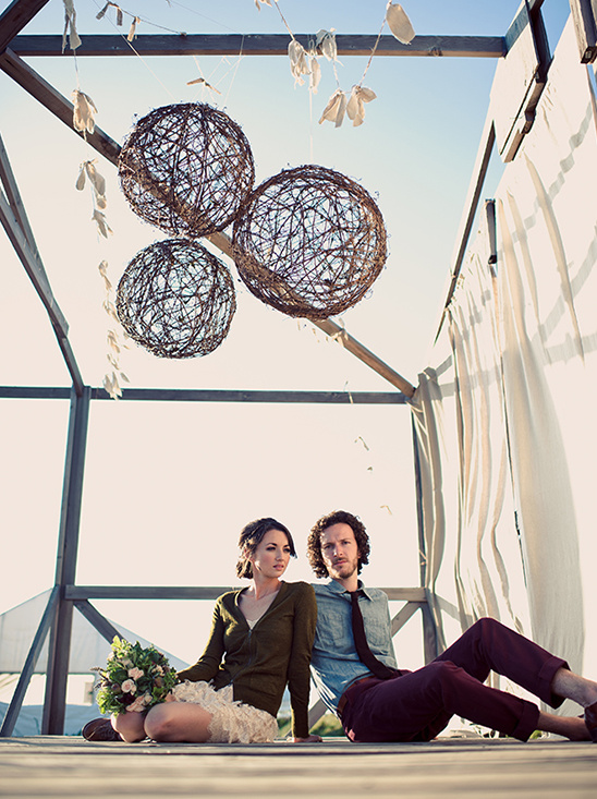 Rustic wedding couple beneath hanging twig balls