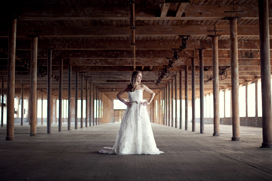 Bride in a white gown poses in rustic warehouse