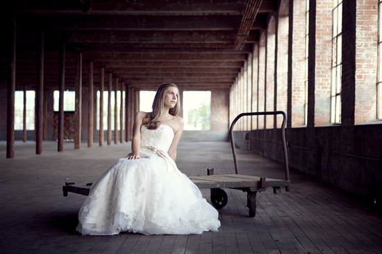 Bride in wedding gown sits in rustic warehouse