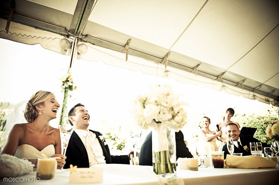 Happy wedding couple laughing with guests at reception