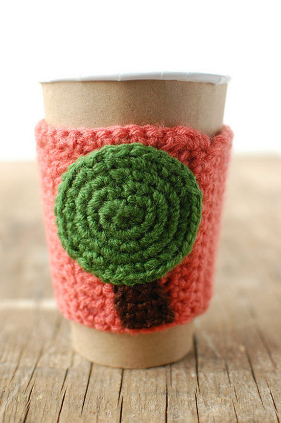 Crocheted tree cozy for a paper coffee cup on wood