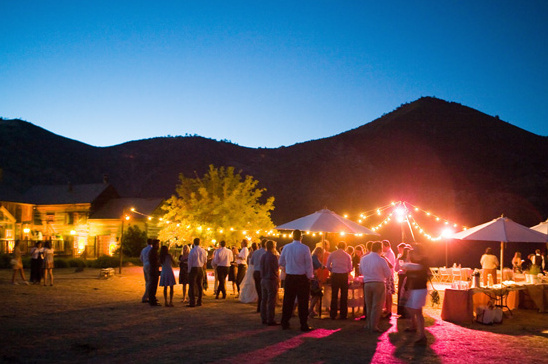 Outdoor wedding reception with string lights at dusk