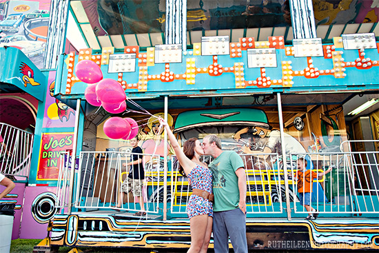 Couple kissing with pink balloons at a carnival, celebrating love