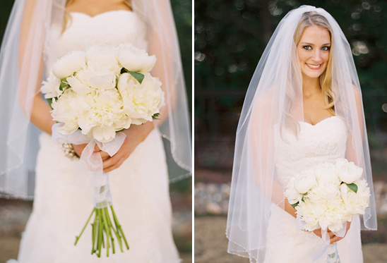 Bride holding white peony bouquet wearing a veil