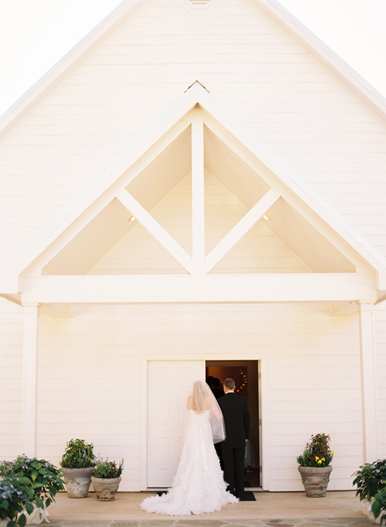 Bride and groom entering white chapel wedding