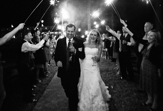Happy couple exits wedding, sparklers ablaze