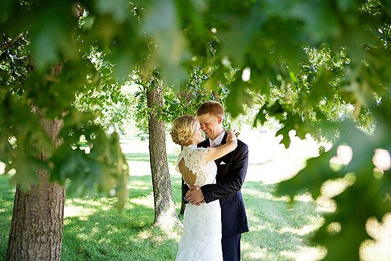 Happy couple embraces under leafy tree, wedding day
