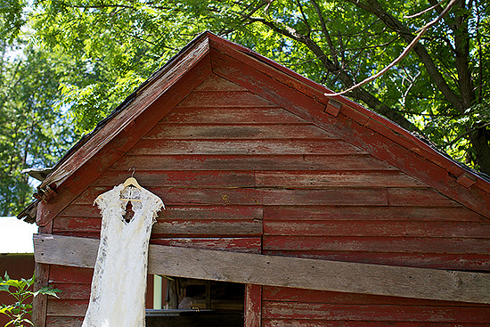 Lace wedding dress hangs on rustic barn