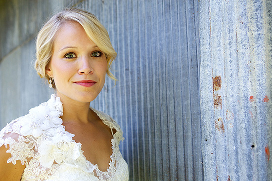 Bride in lace wedding dress against rustic wall