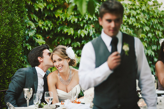 Groom kisses bride during wedding speech reception