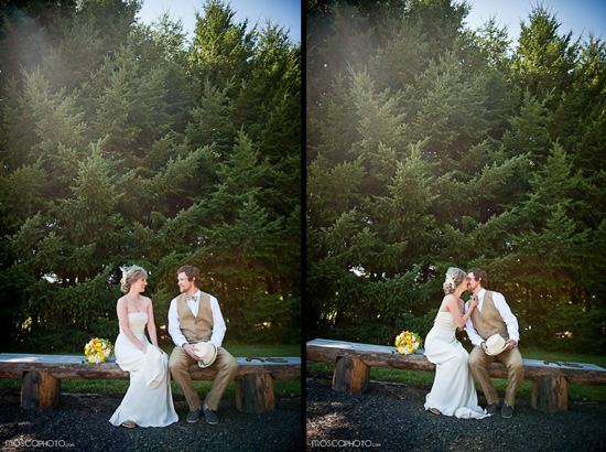 Rustic wedding couple on a bench kissing trees backdrop