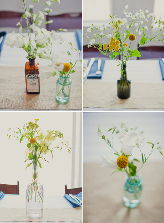 Bottles holding flowers decorate a burlap table runner