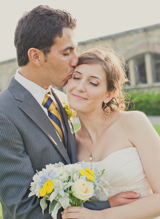 Groom tenderly kisses bride on forehead at wedding