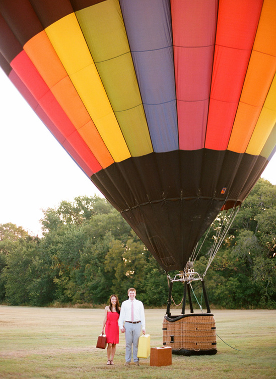 Couple standing with luggage in front of a hot air balloon