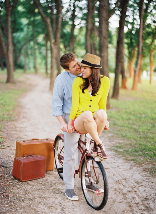 Couple enjoying a bike ride in the park with vintage suitcases