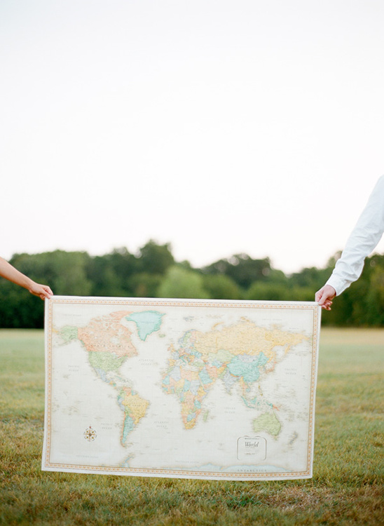 People holding a world map in a field, ready for travel adventures