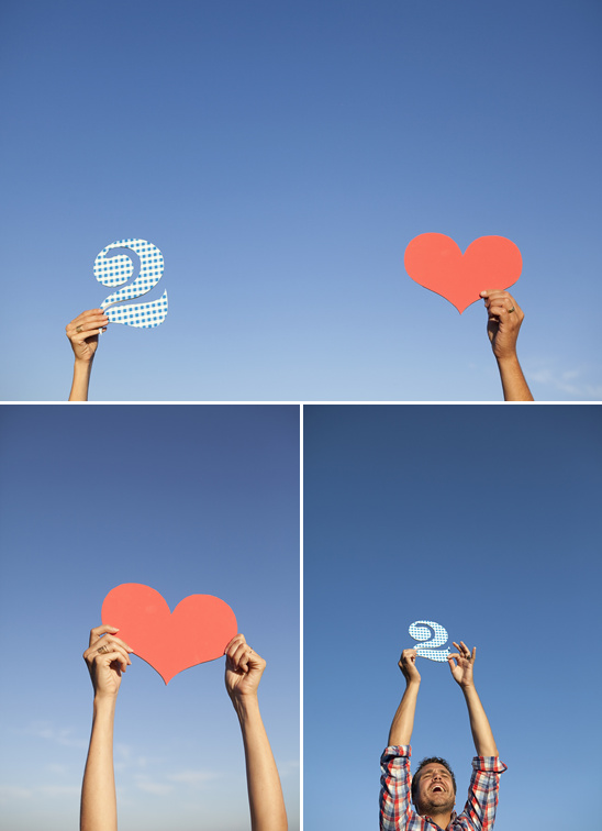 People holding hearts and number two against a blue sky