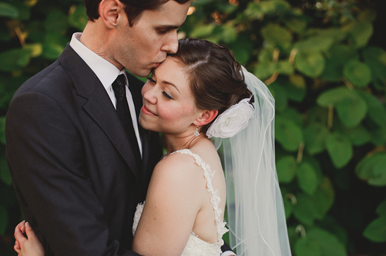 Elegant bride embraced by her groom, wedding day kiss