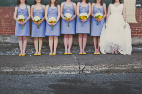 Bridesmaids with blue dresses, yellow shoes, and white bouquets