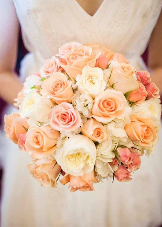 Bride holding a beautiful bouquet of peach and pink roses