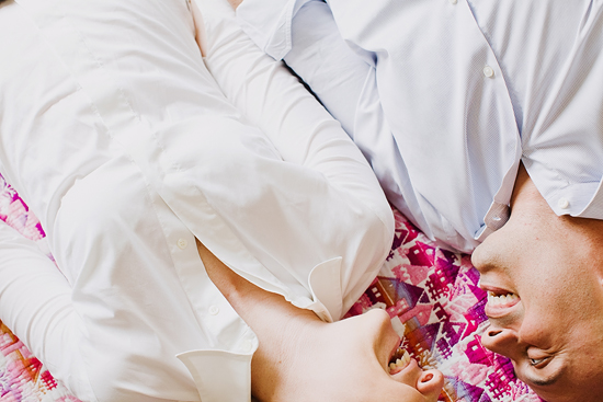 Two people in white shirts lie close together, smiling