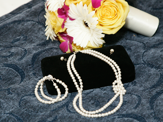 Elegant pearl necklace, bracelet and bouquet on a blue background