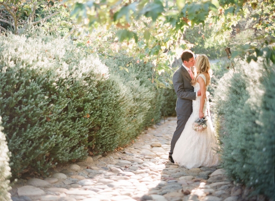 Romantic wedding couple sharing a kiss in a garden setting