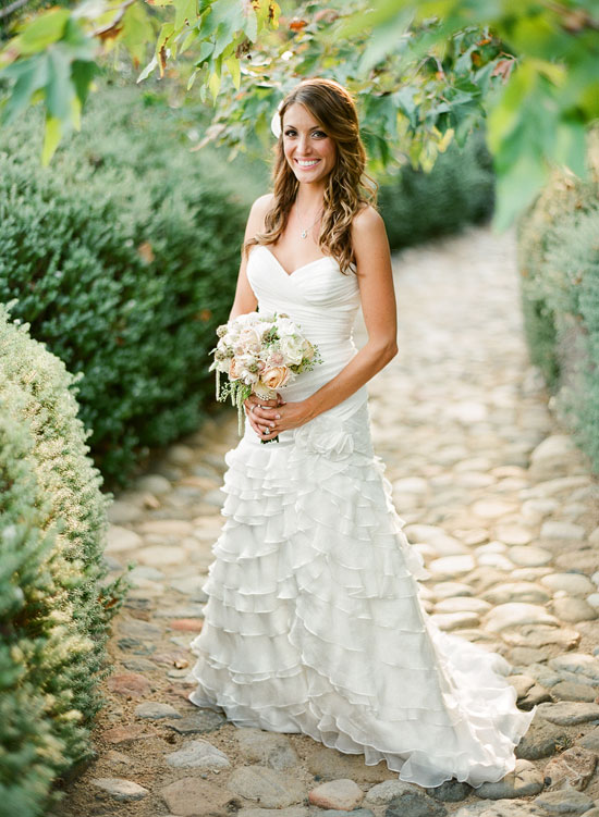 Smiling bride in a gorgeous white wedding dress holding a bouquet