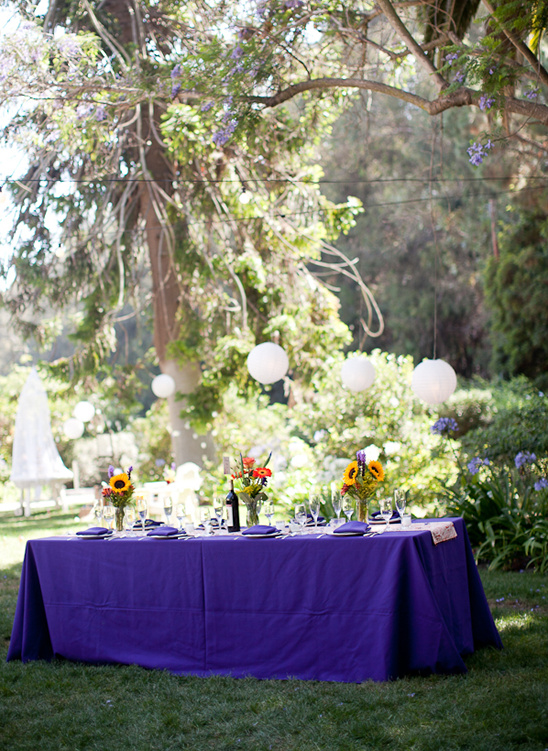 Outdoor wedding table with purple tablecloth and decorations