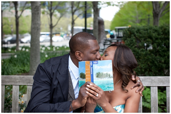 Couple kissing behind a Panama travel book during their engagement