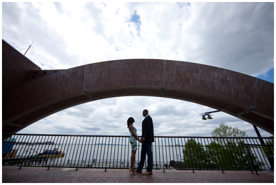 Couple holding hands under a bridge, overlooking the water