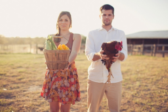 Couple holding fresh produce and chicken on a farm
