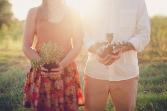 Couple holding plants, ready to start planting in a sunny field