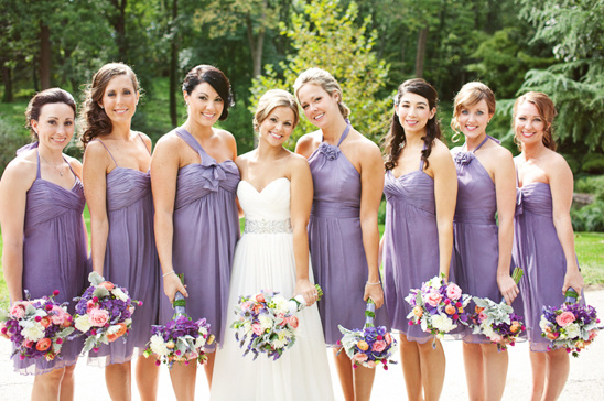A bride with bridesmaids in purple dresses holding floral bouquets