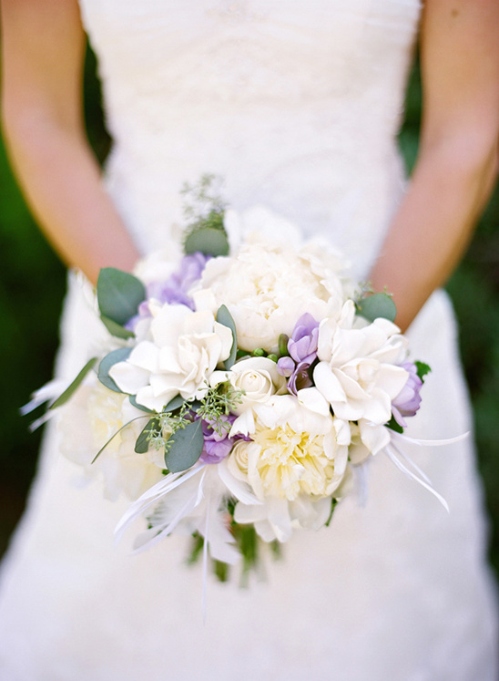 Bride holding a beautiful bouquet of white and purple flowers