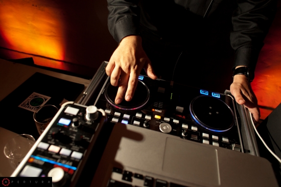 DJ mixing music with hands on a soundboard setup, laptop nearby
