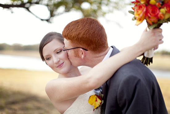 Groom kisses happy bride on wedding day outside